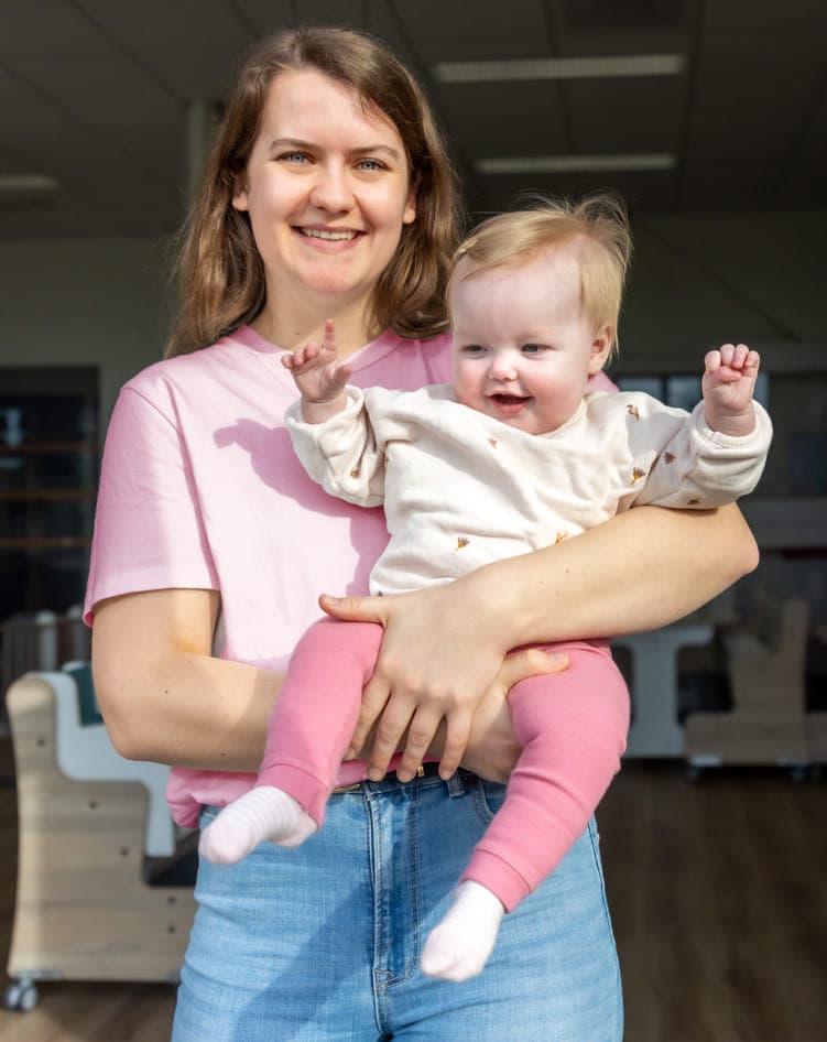 Blij kind op de armen bij een pedagogisch medewerker bij kinderopvang Kind&co ludens