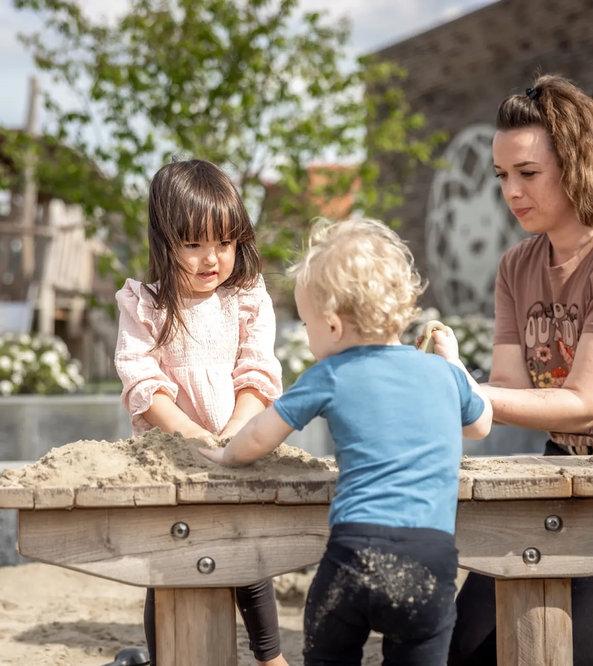 Kinderen spelen in zandbak met pedagogisch medewerker bij Kind&co ludens
