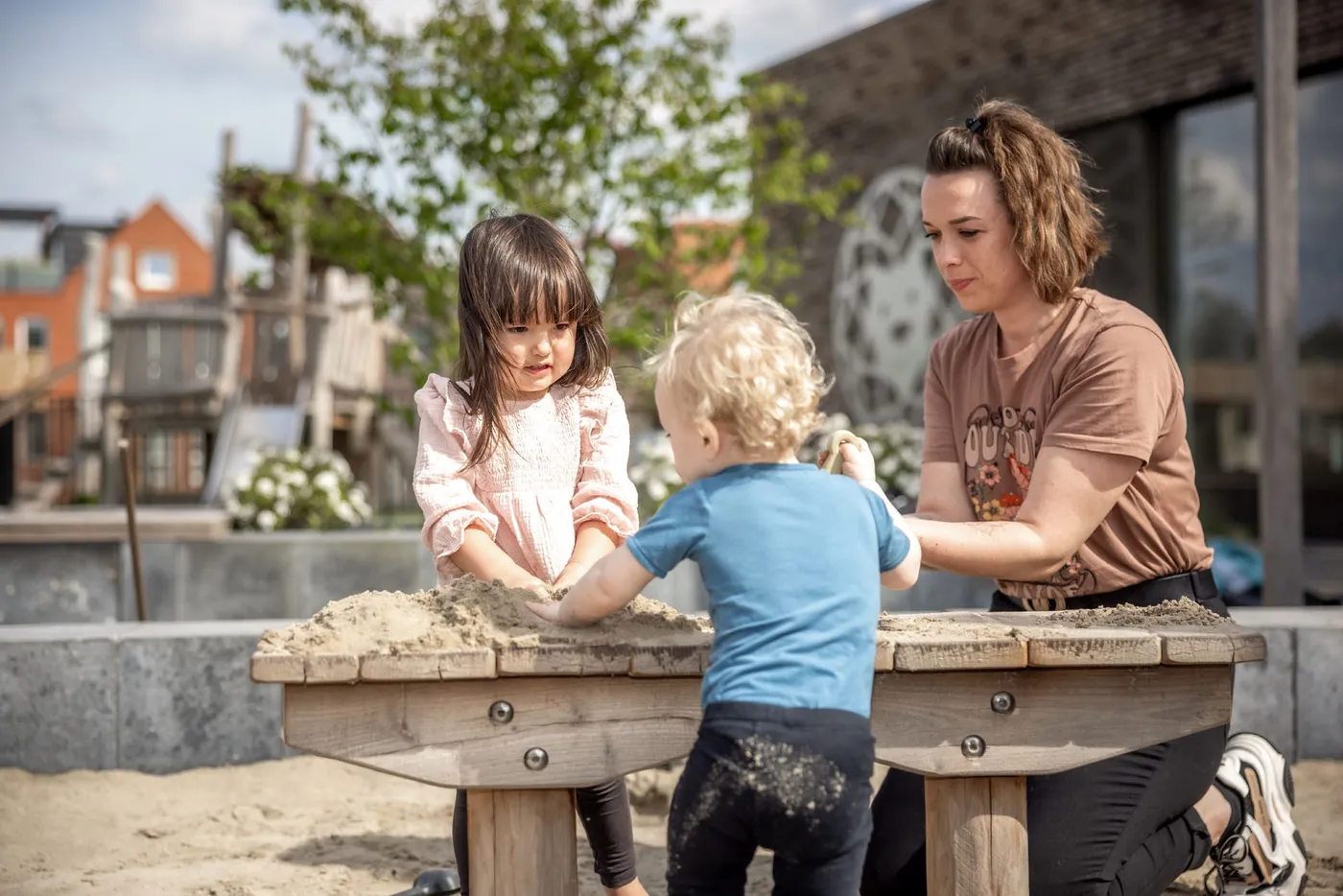 Kinderen spelen in zandbak met pedagogisch medewerker bij Kind&co ludens